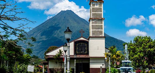 The church of the town of La Fortuna with the conic shape of the Arenal Volcano in the background. Costa Rica
